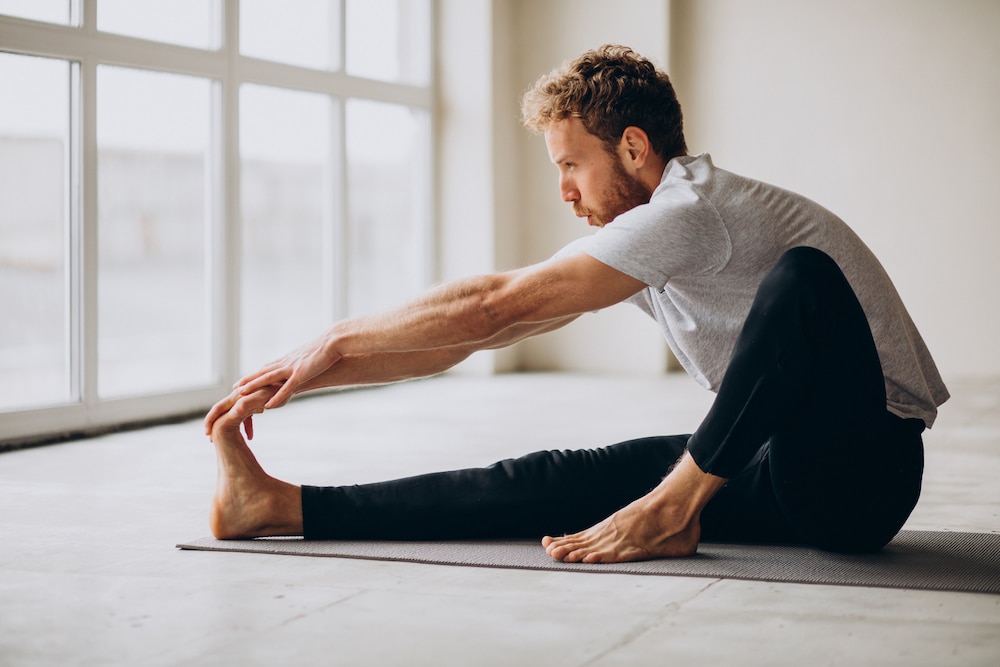 Man practicing yoga on the mat at home. Flexibility (Proteins, eiwitten)